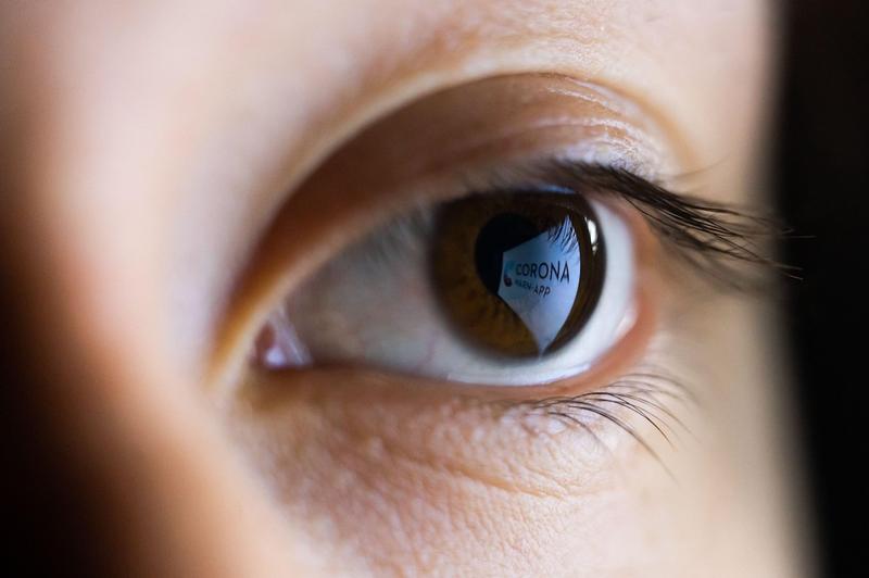 Aplicație de contact tracing reflectată în ochiul unei femei