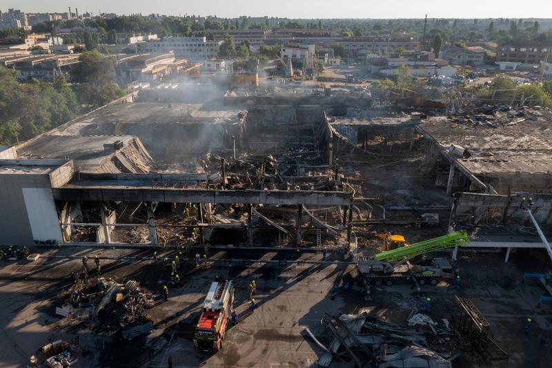 Pompierii Serviciului de Stat pentru Situații de Urgență din Ucraina lucrează pentru a îndepărta resturile de la un centru comercial ars în urma unui atac cu rachete în Kremenciuk