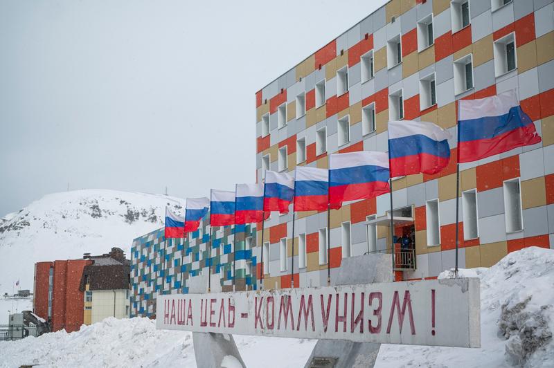 O pancartă în limba rusă pe care scrie Comunismul este țelul  nostru din fața unei clădiri cu steaguri rusești din orașul minerilor Barentsburg, în Arhipelagul Svalbard, în nordul Norvegiei