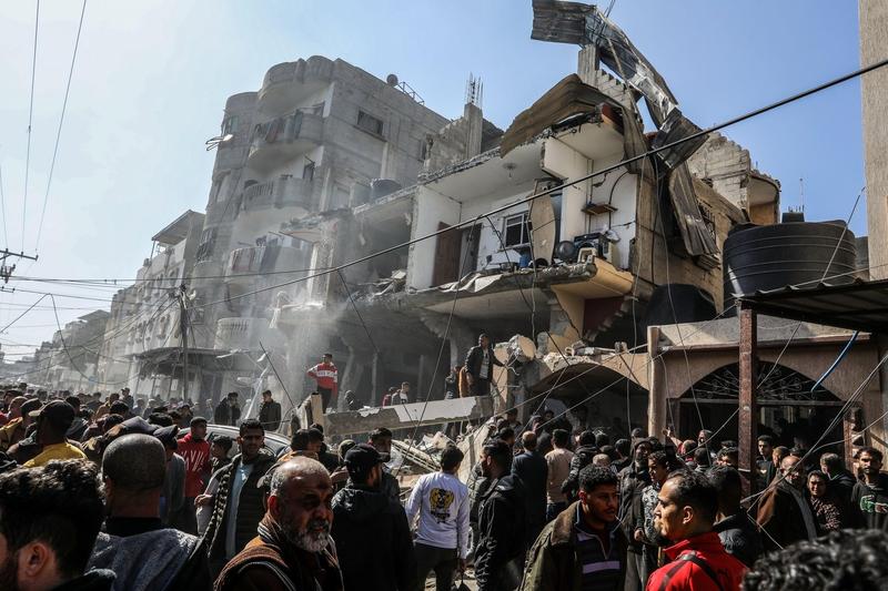 Civili palestinieni lângă o clădire distrusă de un bombardament israelian în Rafah