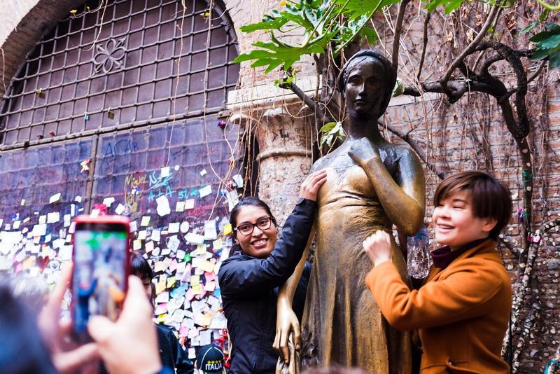 Turiști fotografiindu-se cu statuia Julietei din Verona, Italia