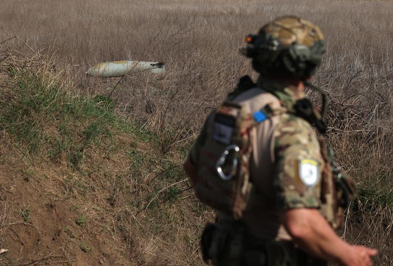 Soldat ucrainean care se uită la o bombă rusească FAB-500 neexplodată