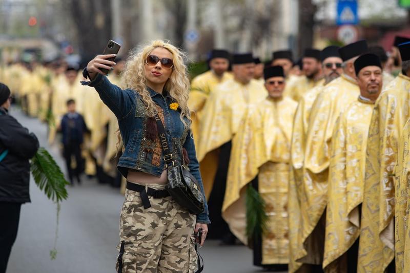 O tânără își face un selfie lângă e procesiune de Paște în București