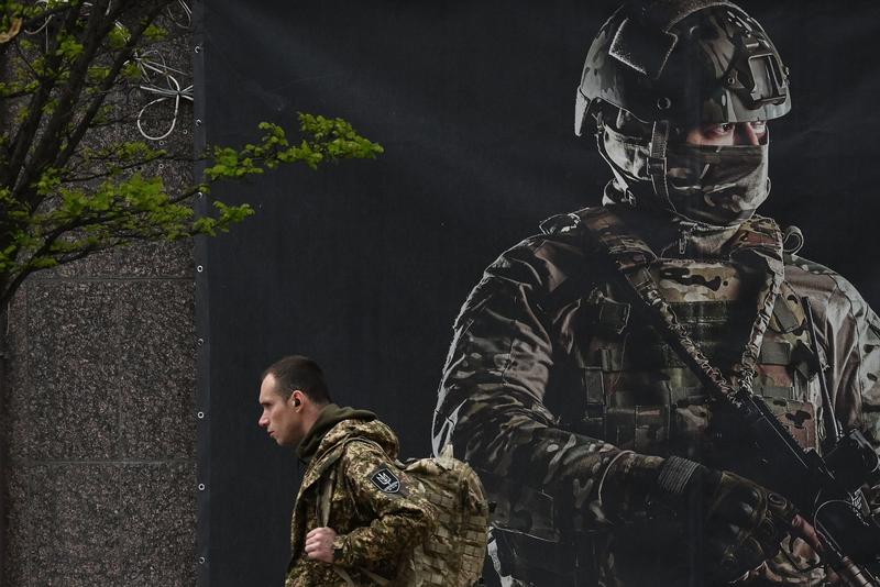 Militar ucrainean, în fața unui poster pentru recrutare 