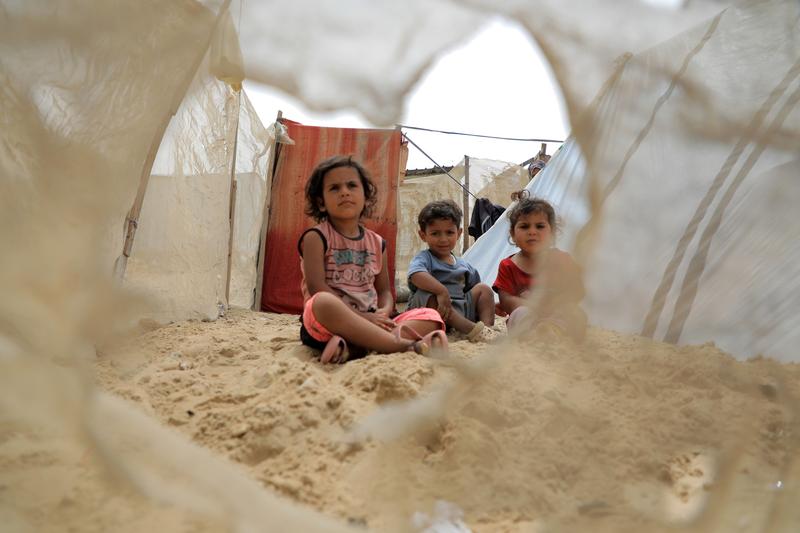 Trei copii palestinieni evacuați din Rafah sunt văzuți pe o plajă din orașul Khan Younis din sudul Fâșiei Gaza, pe 10 mai 2024.