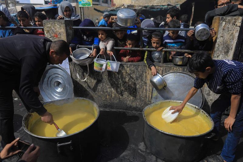Copii palestinieni strămutați se adună pentru a primi alimente la un punct de donații din Rafah, în sudul Fâșiei Gaza, pe 7 martie 2024.