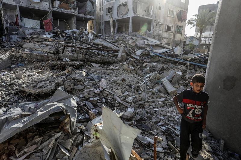 Un copil palestinian se plimbă printre dărâmăturile clădirilor distruse de atacurile israeliene, în Deir al Balah, Gaza, pe 14 mai 2024. 