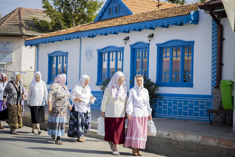 Localnici trec pe lângă punctul gastronomic local La Grisha, din Ghindărești, Constanța