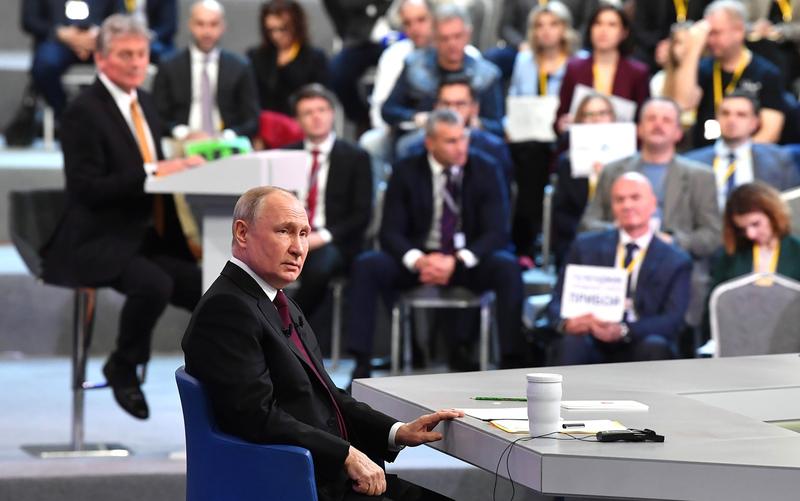 Vladimir Putin la un eveniment la care a participat si Dmitri Peskov, purtatorul sau de cuvant (in stanga)