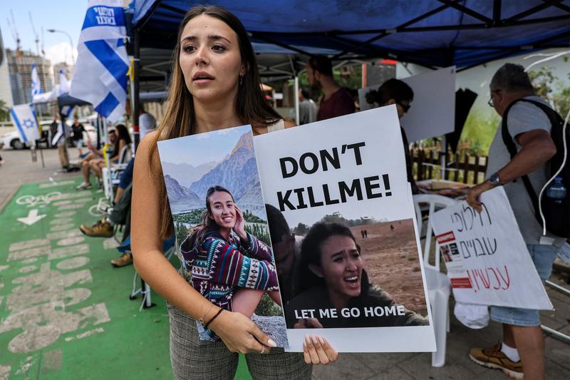 O prietenă a studentei israeliene Noa Argamani, răpită de Hamas în asaltul din 7 octombrie, ține o pancartă cu chipul tinerei, la o demonstranție din Tel Aviv, pe 18 octombrie 2023.